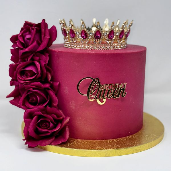 Elegant dark pink birthday cake with a crown and roses.