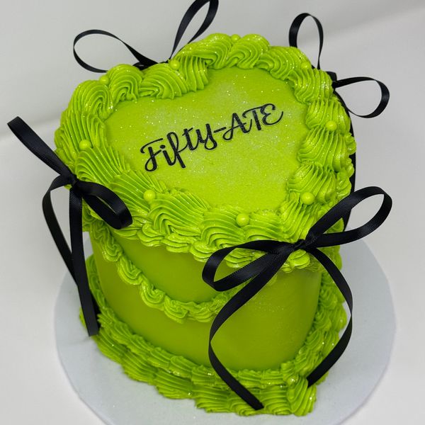 Heart-shaped green cake with black bows and "Fifty-ATE" text.
