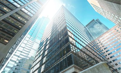 Sunlit modern skyscrapers with reflective glass windows in a city.
