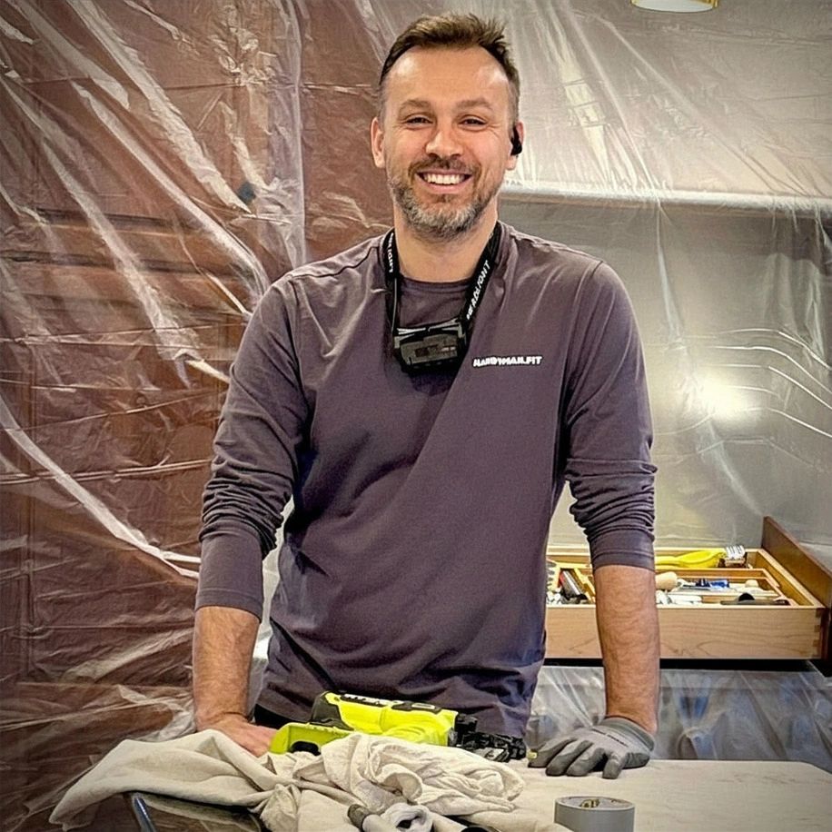 Man smiling during home renovation work with tools and protective gloves.
