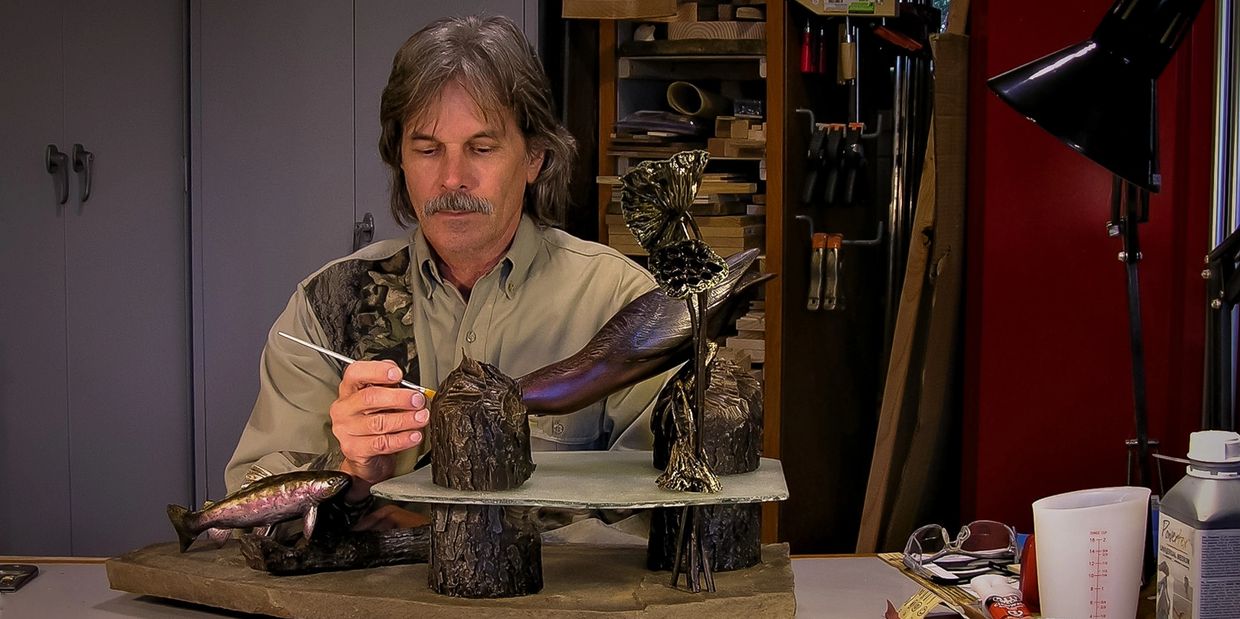 Artist Painting a Green Heron and Trout Sculpture