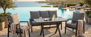 Outdoor seating area by a pool with a table, chairs, and scenic ocean view.