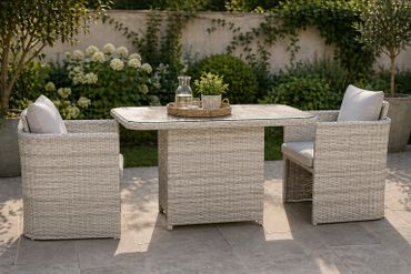 Outdoor wicker patio set with table and two cushioned chairs.
