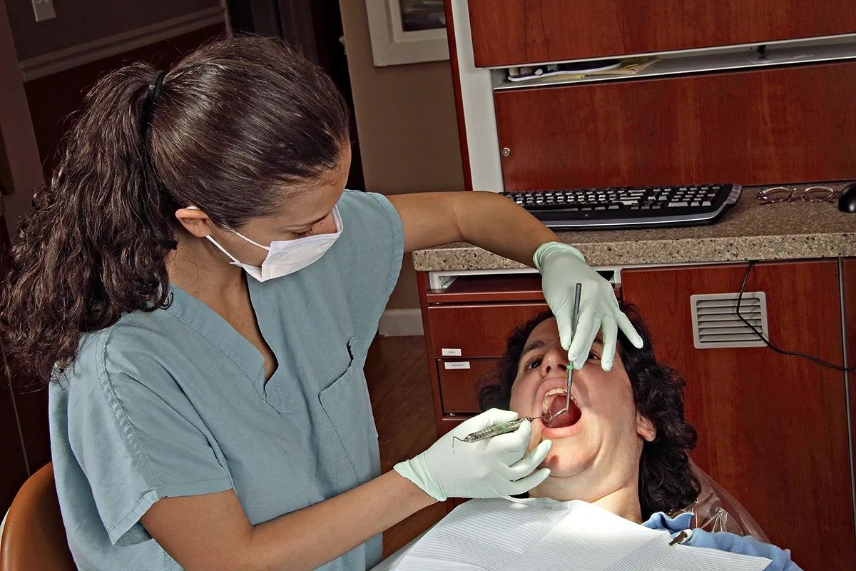 Dental hygienist cleaning patient's teeth.