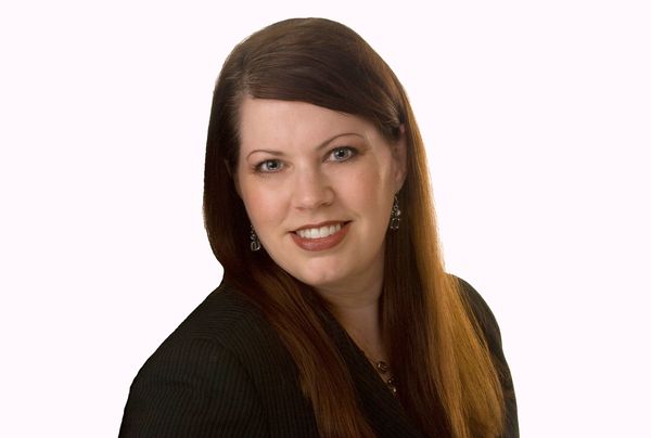 Smiling woman with long brown hair in black attire.