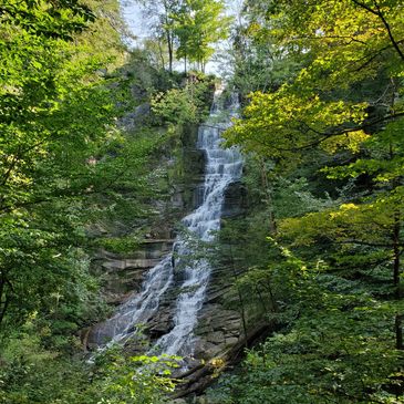 A serene waterfall cascading down rocky cliffs surrounded by lush green forest.