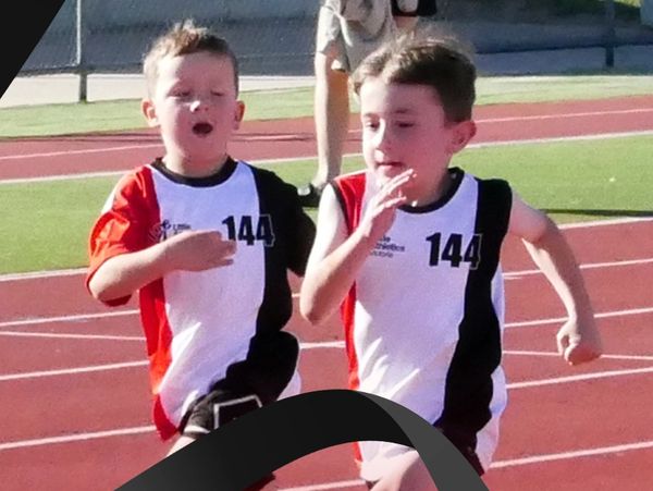 Two boys racing on a track with jerseys numbered 144.