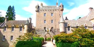 Historic stone castle with turrets under a bright blue sky.