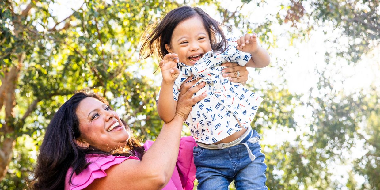 Mom holding child with disability and laughing