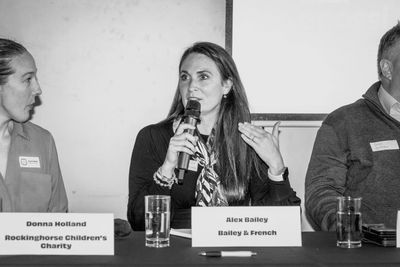 Woman speaking at a panel discussion with name tags in front.