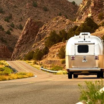 Outdoorsy Ad. RV driving down the road between mountains