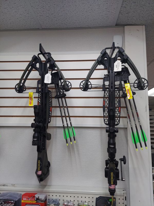 Two black crossbows hanging on display with arrows.