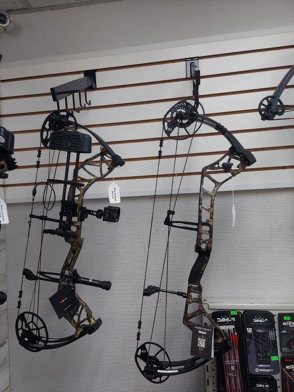 Two compound bows hanging on display wall.