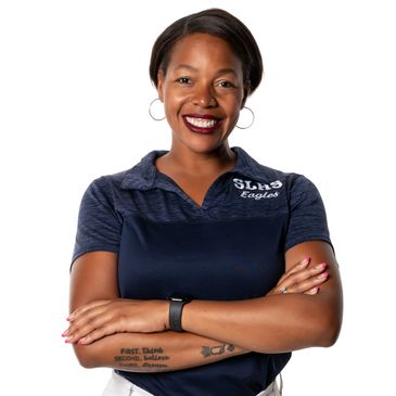 Confident woman in a navy polo shirt with arms crossed, smiling.