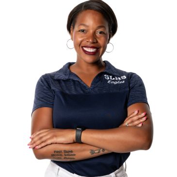 Confident woman in a navy polo shirt with arms crossed, smiling.