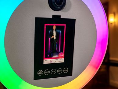 A photo booth with a colorful ring light and digital screen.