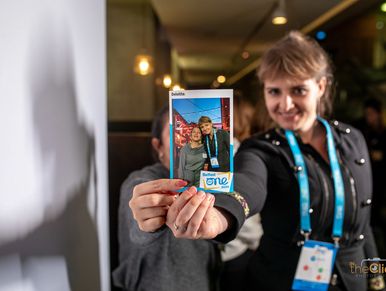 Woman holding a photo of two people at an event.
