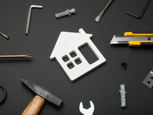 White house cutout surrounded by various hand tools on a black background.