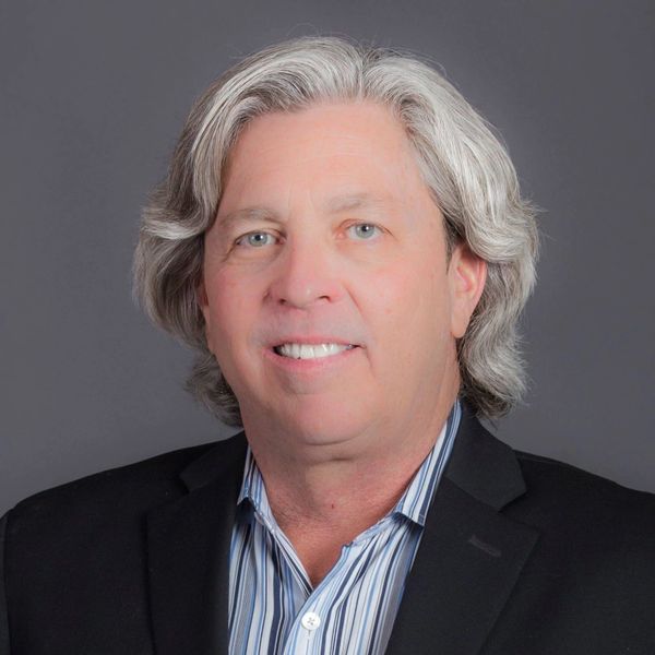 Middle-aged man with gray hair wearing a black suit jacket and striped shirt.