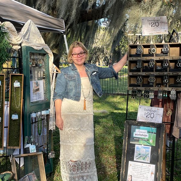 Woman selling handmade jewelry outdoors.