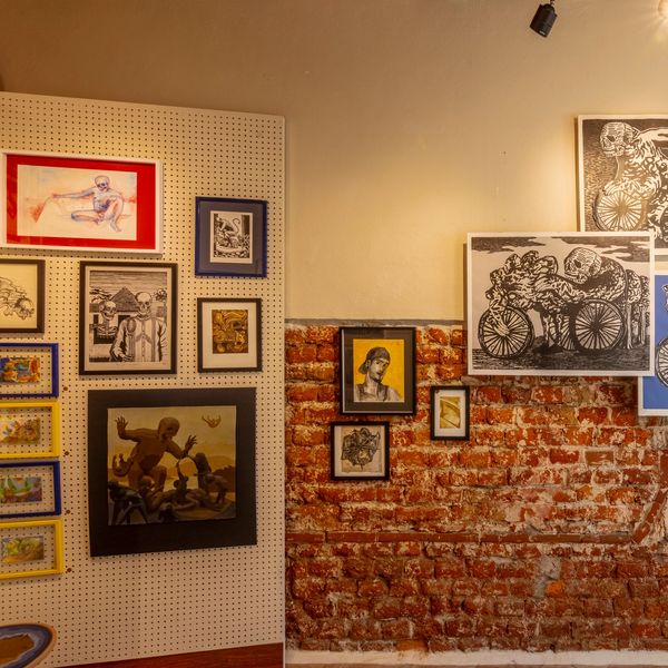 Galería con cuadros y arte en paredes de ladrillo y panel blanco.