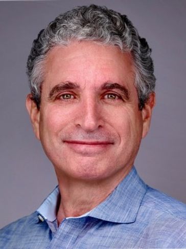 Smiling middle-aged man with gray curly hair wearing a blue shirt.