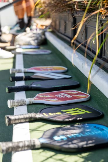 Pickleball paddles lined up on a court.