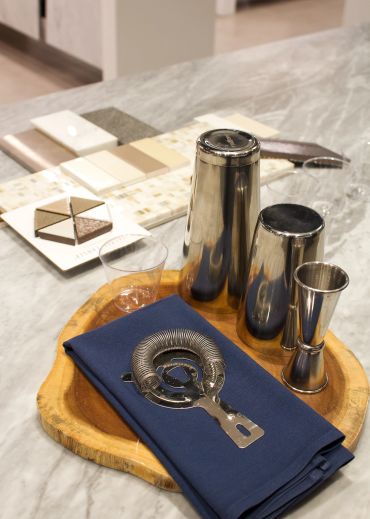 Bartender tools on a wooden tray with a blue napkin.