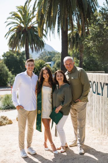 Family celebrating graduation outdoors with palm trees.
