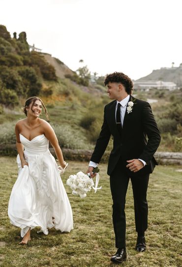 Bride and groom happily walking outdoors.