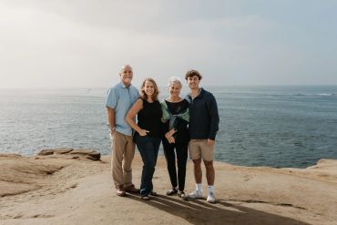 Family posing together on a rocky beach.