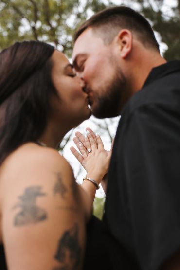 Couple sharing a tender kiss with hands touching.