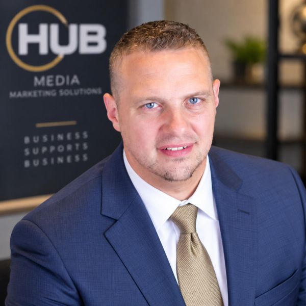 Professional man in a suit with HUB Media backdrop.