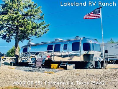 Shiny silver Airstream RV parked at Lakeland RV Ranch with American flag flying.