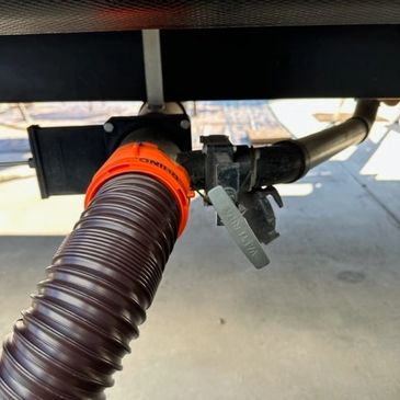 A flexible hose connected to a valve under a vehicle or trailer.