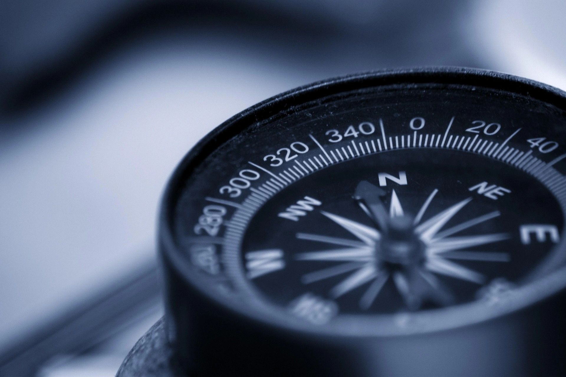 Close-up of a black compass showing cardinal directions.
