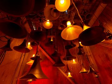 Various hanging brass horns with warm lighting.