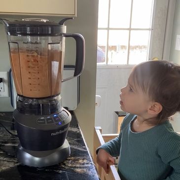Toddler watching a blender on a kitchen counter.