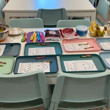 Art supplies and snacks set up on a table for kids.