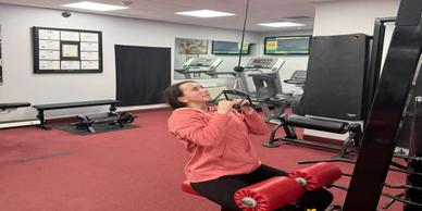 Woman exercising on a lat pulldown machine in a gym.