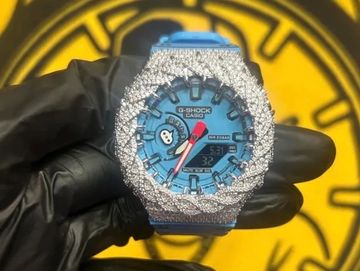 Diamond-encrusted G-Shock watch held by gloved hand.