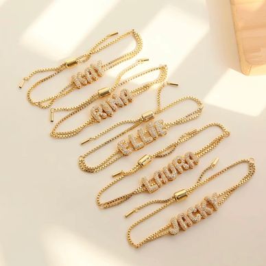 Gold name bracelets with diamond-like letters.