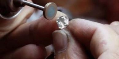 Person holding a rough diamond and polishing it.