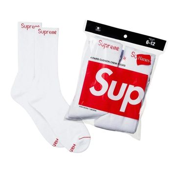 White Supreme socks with red logo, next to their package.