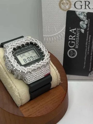 Digital watch encrusted with diamonds on a cushion.