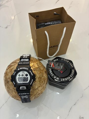 Black G-Shock digital watch with packaging and bag.
