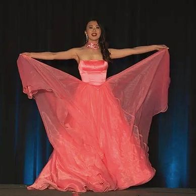Wearing a pink gown, AMP delegate holds the gown overlay as she spins. 