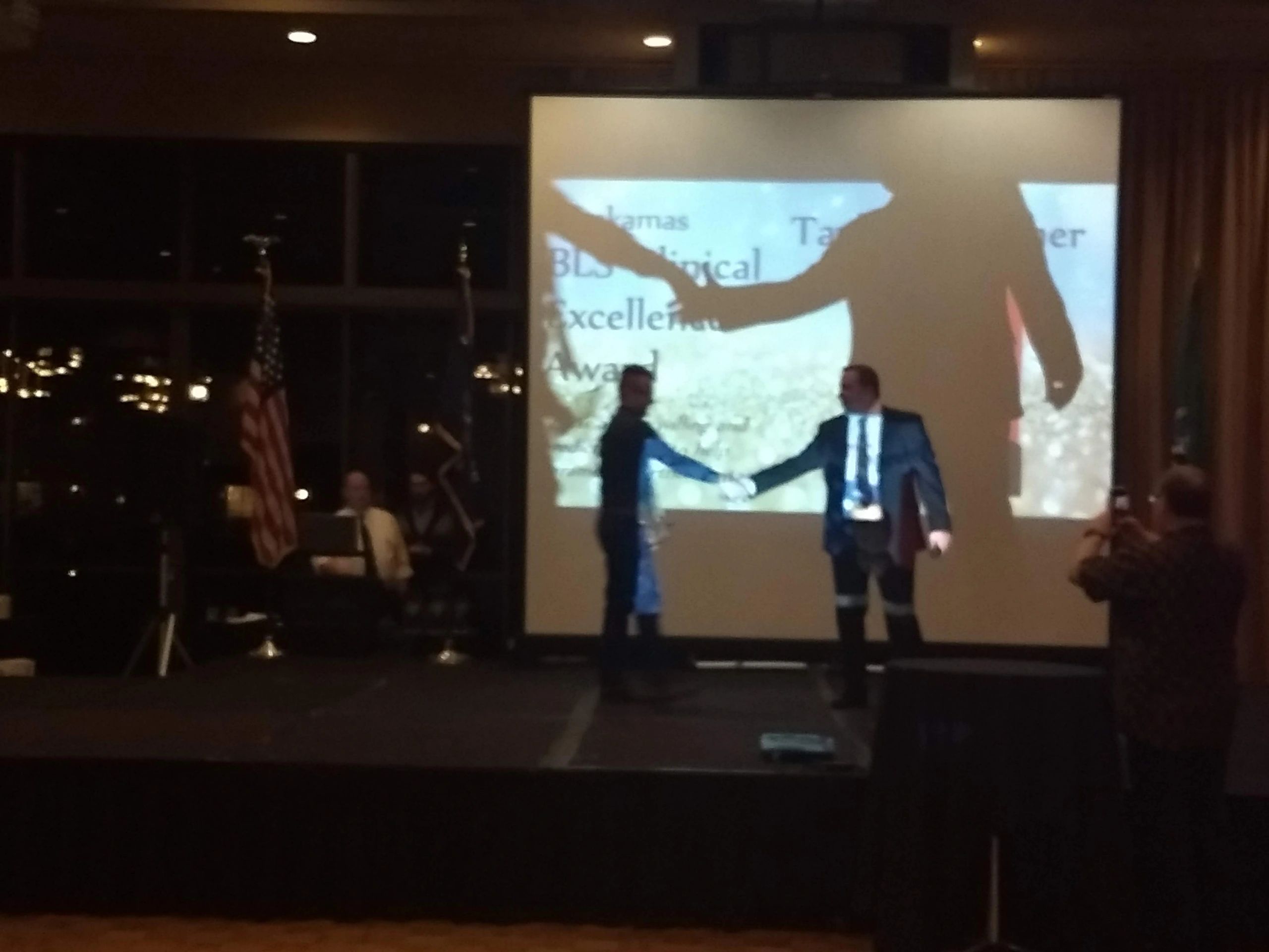 Two people shaking hands on stage during an award ceremony.