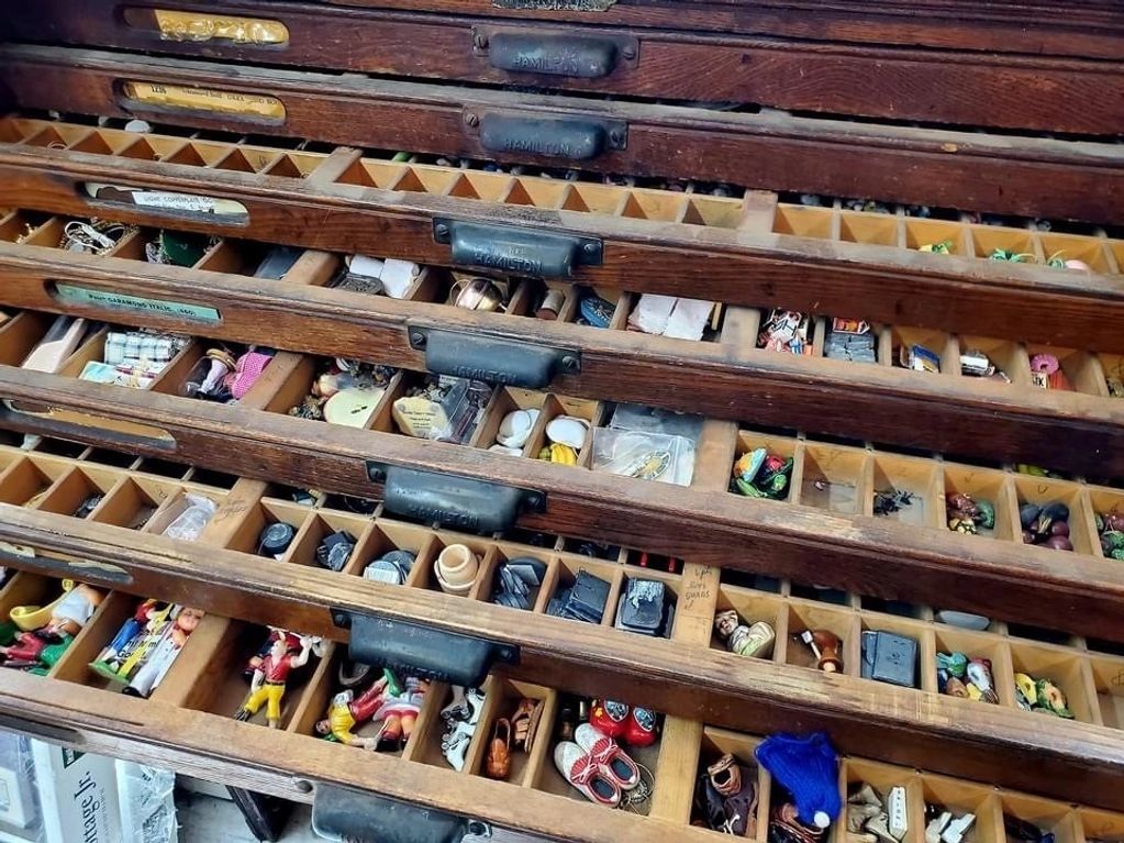Vintage miniature collectibles stored in an antique typesetter cabinet