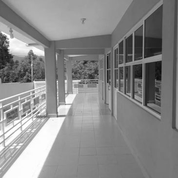 Empty corridor with large windows and railing, bathed in sunlight.